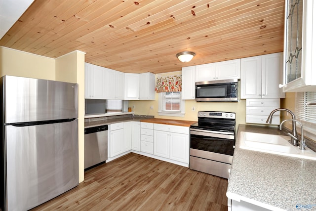 kitchen with a sink, appliances with stainless steel finishes, light wood-style flooring, and white cabinetry