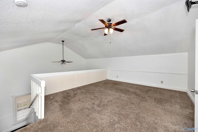 additional living space with lofted ceiling, baseboards, dark carpet, and a textured ceiling