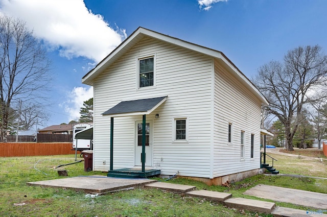 rear view of house featuring a yard and fence