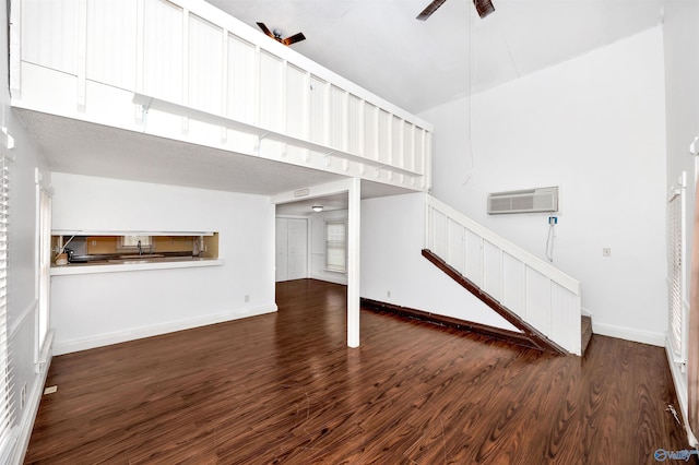 unfurnished living room with wood finished floors, a ceiling fan, baseboards, and a wall mounted air conditioner