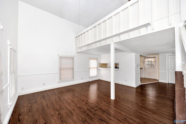 unfurnished living room featuring a high ceiling, wood finished floors, and baseboards