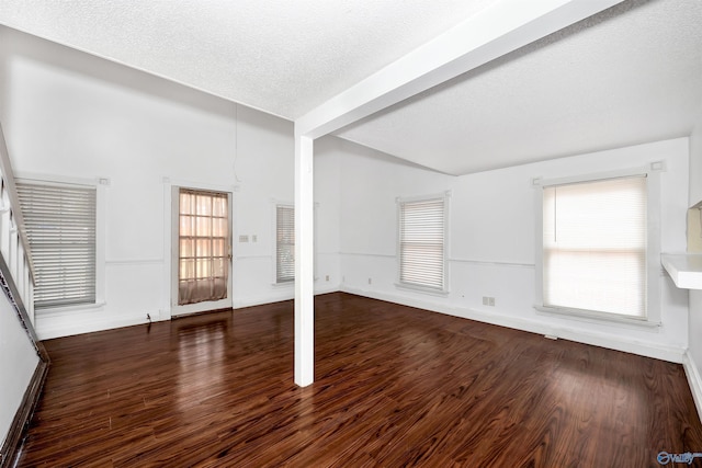 empty room featuring vaulted ceiling, a textured ceiling, baseboards, and wood finished floors