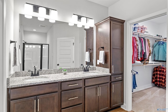 24009 Quints Dr, Athens, AL 35613 - bathroom featuring double vanity, a walk in closet, a shower stall, and baseboards
