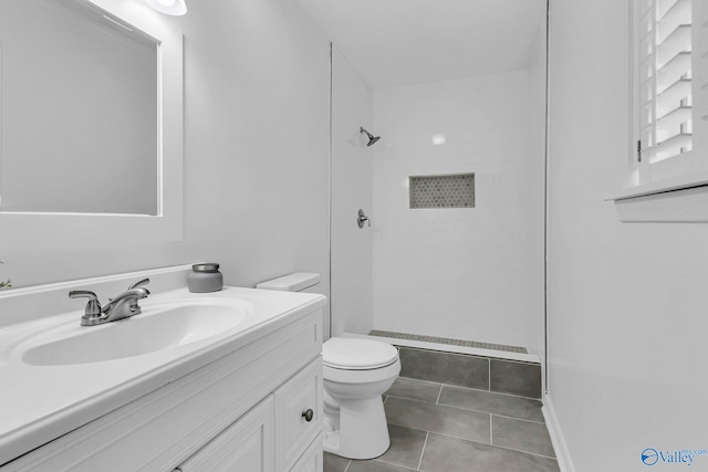 bathroom with vanity, a tile shower, tile patterned floors, and toilet