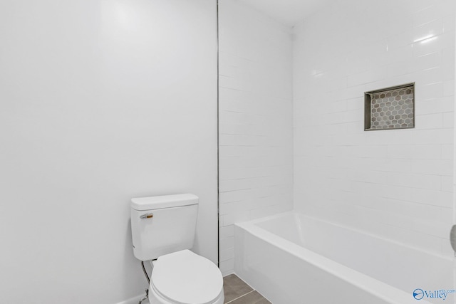 bathroom featuring toilet, tiled shower / bath combo, and tile patterned flooring