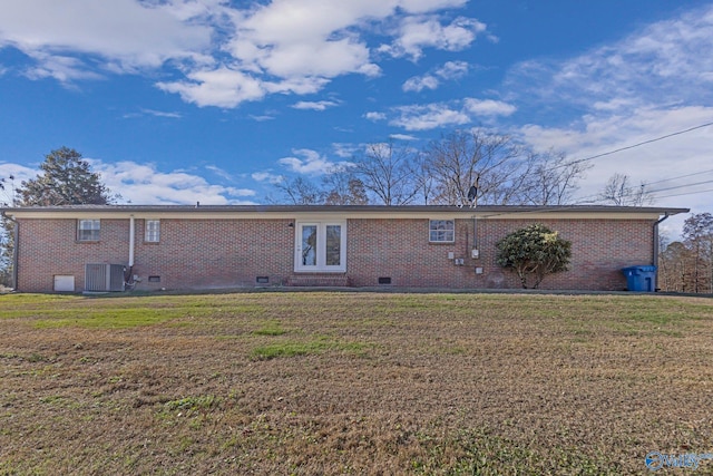 rear view of house featuring central AC unit and a yard