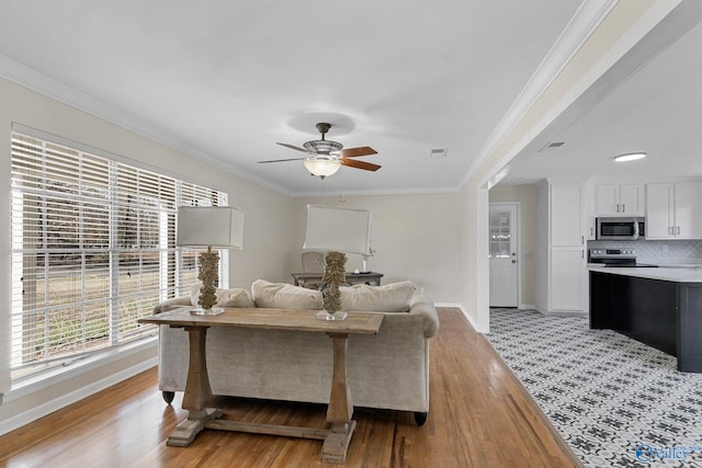 living room featuring ceiling fan, ornamental molding, and light hardwood / wood-style flooring