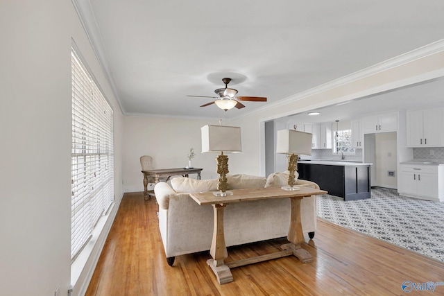 living room with crown molding, ceiling fan, sink, and light hardwood / wood-style flooring