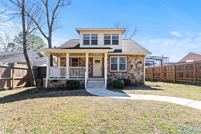 bungalow with covered porch, a fenced backyard, stone siding, and a front yard