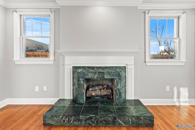 interior details with ornamental molding, a fireplace, baseboards, and wood finished floors