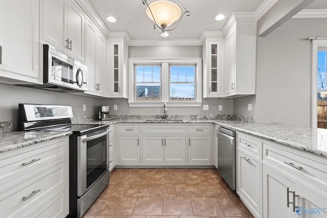 kitchen with white cabinets, glass insert cabinets, ornamental molding, stainless steel appliances, and a sink