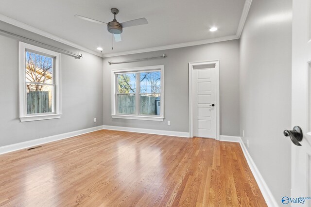 empty room featuring a ceiling fan, baseboards, visible vents, light wood-type flooring, and crown molding