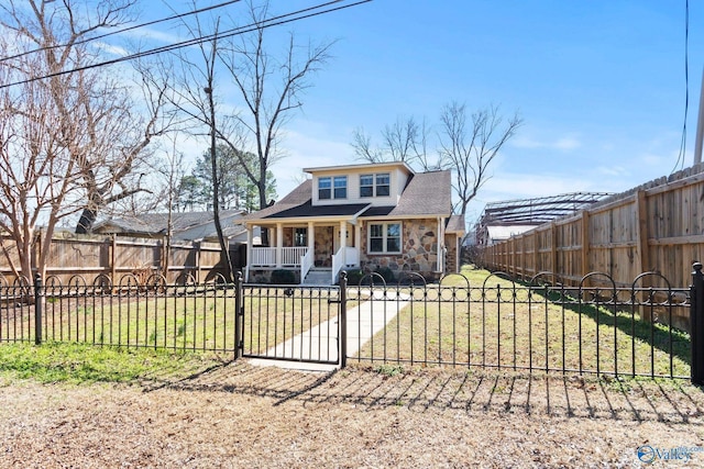 view of front of house featuring a fenced front yard, covered porch, stone siding, a gate, and a front yard