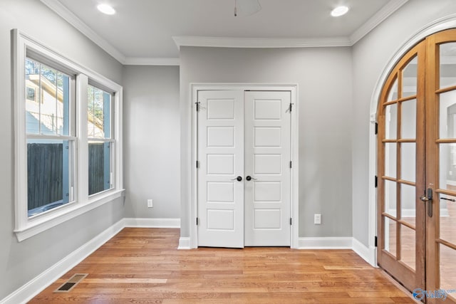 interior space featuring ornamental molding, light wood-type flooring, visible vents, and baseboards