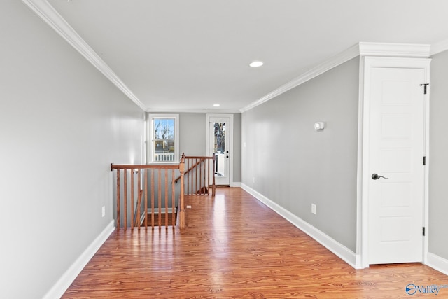 corridor featuring light wood-type flooring, baseboards, crown molding, and an upstairs landing