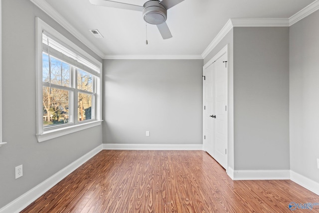 unfurnished room with baseboards, visible vents, ornamental molding, and wood finished floors