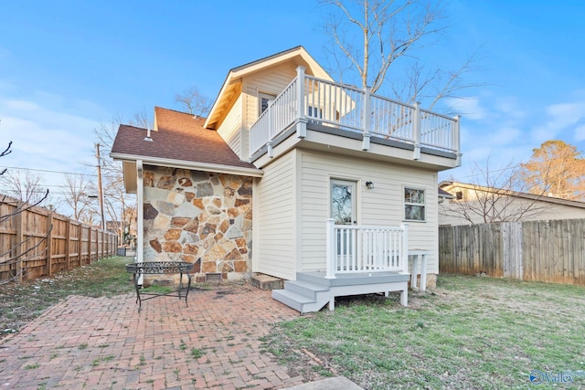 back of house featuring a fenced backyard, a yard, and a balcony