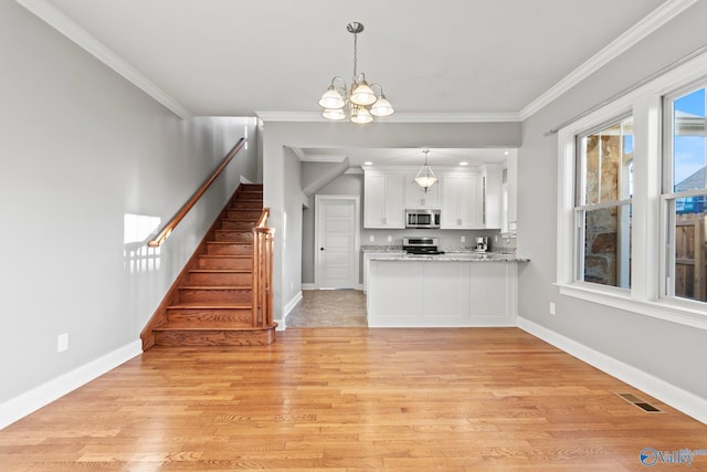 kitchen with stainless steel appliances, visible vents, light wood-style flooring, ornamental molding, and white cabinetry