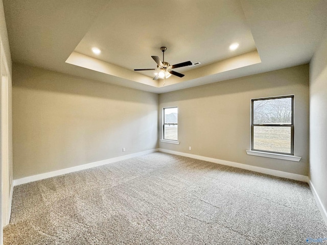 carpeted spare room with ceiling fan and a raised ceiling