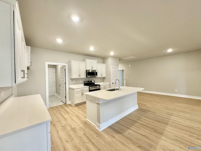 kitchen featuring sink, white cabinets, a kitchen island with sink, light hardwood / wood-style floors, and stainless steel appliances