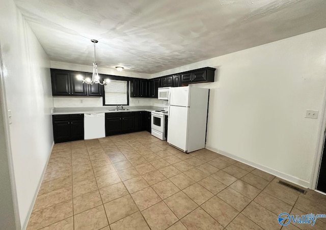 kitchen with hanging light fixtures, light tile patterned floors, sink, white appliances, and an inviting chandelier