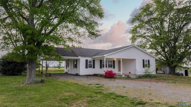 back of house with a yard, driveway, a porch, and an attached carport