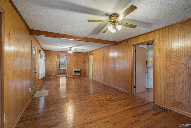 unfurnished living room featuring heating unit, wood finished floors, visible vents, a textured ceiling, and ceiling fan