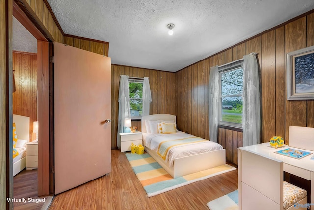 bedroom with wooden walls, wood finished floors, and multiple windows