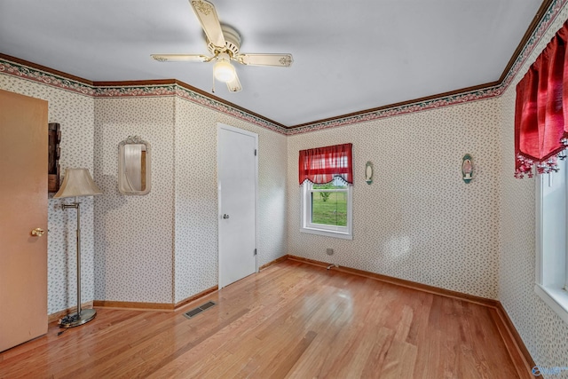 unfurnished bedroom with ceiling fan, crown molding, wood finished floors, and visible vents
