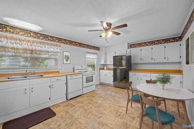 kitchen with a ceiling fan, a sink, white appliances, stone finish flooring, and a textured ceiling