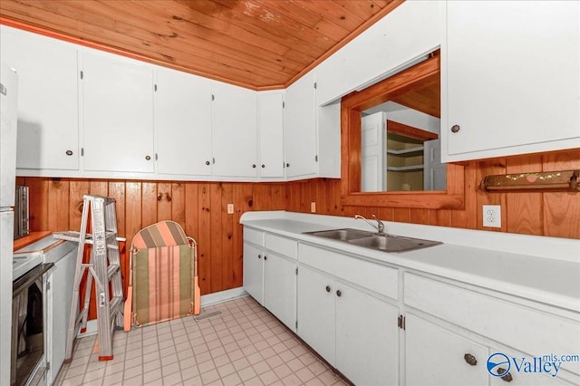 kitchen featuring wood walls, wood ceiling, light countertops, and a sink