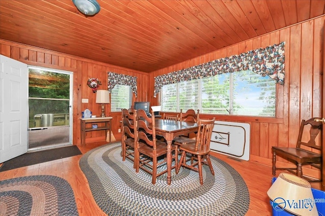 dining space with wooden ceiling, light wood-style floors, and wood walls