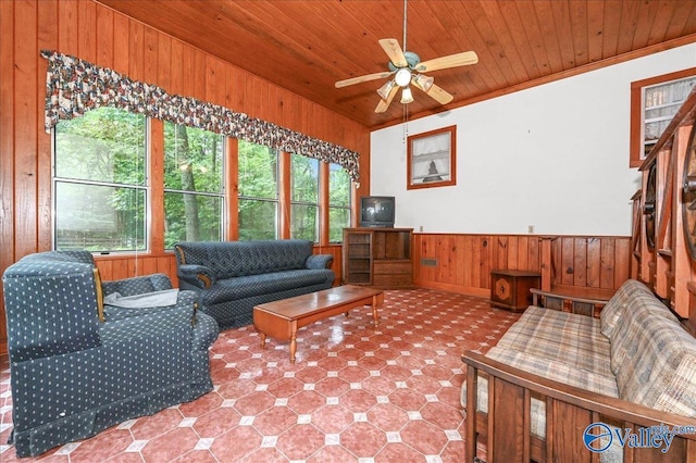 living area featuring wooden walls, ceiling fan, ornamental molding, wood ceiling, and wainscoting