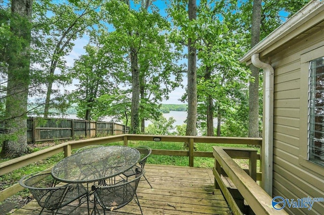 wooden deck with outdoor dining area, fence, and a water view