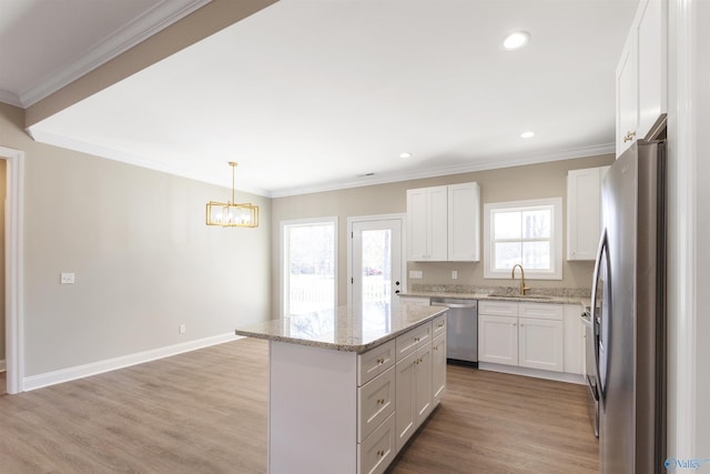kitchen with a center island, ornamental molding, stainless steel appliances, and a sink