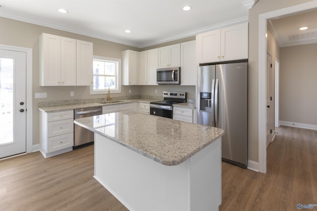 kitchen featuring visible vents, a sink, a kitchen island, stainless steel appliances, and white cabinets