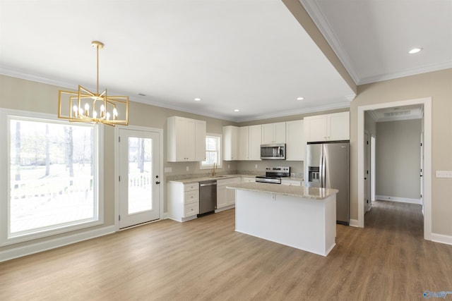 kitchen with light wood-type flooring, a sink, white cabinetry, stainless steel appliances, and an inviting chandelier