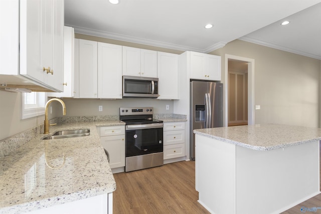 kitchen with ornamental molding, a sink, white cabinets, light wood-style floors, and appliances with stainless steel finishes