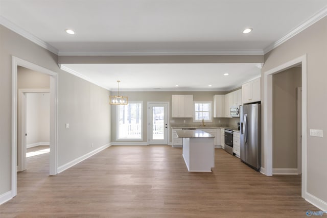 kitchen featuring a kitchen island, appliances with stainless steel finishes, light wood-style floors, white cabinets, and a sink