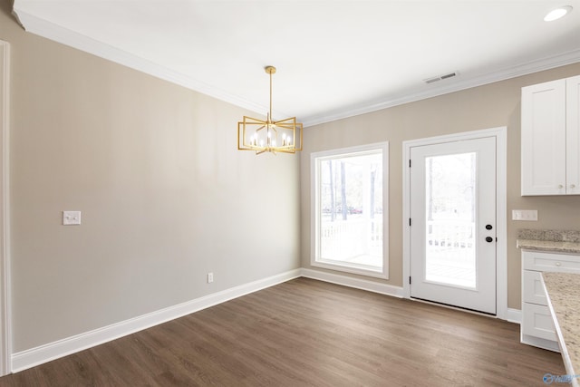 unfurnished dining area featuring dark wood finished floors, an inviting chandelier, crown molding, and visible vents