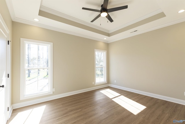 unfurnished room featuring wood finished floors, visible vents, baseboards, ornamental molding, and a raised ceiling