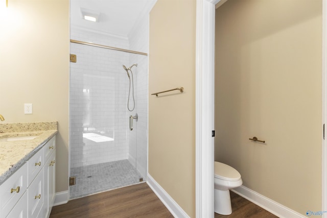 bathroom featuring a stall shower, toilet, vanity, and wood finished floors
