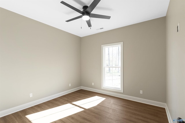 spare room featuring visible vents, baseboards, ceiling fan, and dark wood-style flooring