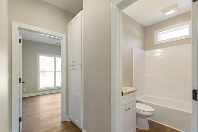 full bathroom with bathtub / shower combination, toilet, wood finished floors, and vanity