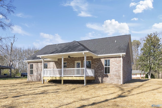 view of front of home featuring a wooden deck, brick siding, roof with shingles, and ceiling fan