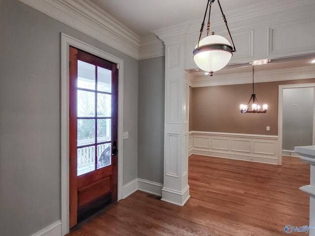 foyer featuring ornamental molding, wood-type flooring, and a notable chandelier