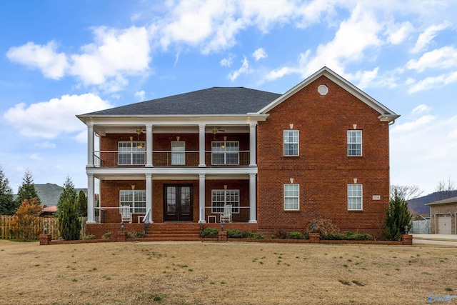 view of front facade with a front yard, french doors, a balcony, and a porch