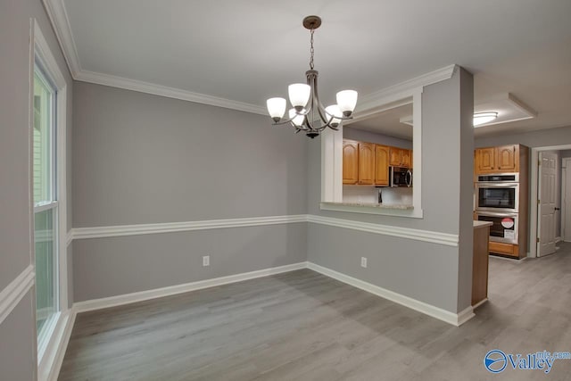 unfurnished dining area featuring light wood finished floors, baseboards, a chandelier, and ornamental molding