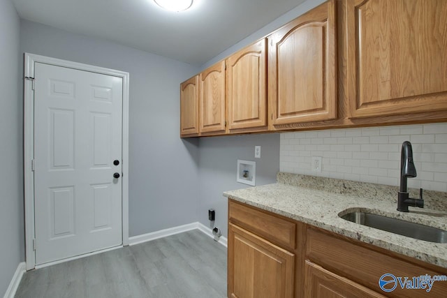 laundry room featuring hookup for a washing machine, a sink, baseboards, cabinet space, and light wood finished floors