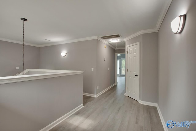 hallway featuring crown molding, visible vents, attic access, light wood-type flooring, and baseboards